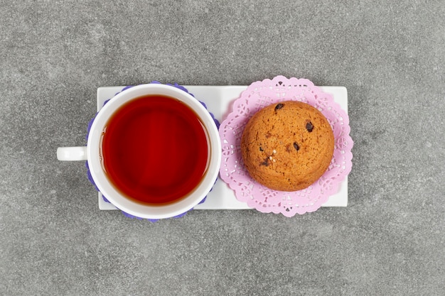 Tasse Tee und Kekse auf weißer Untertasse