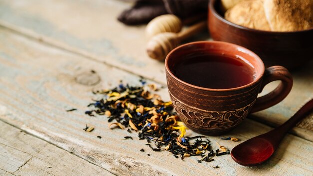 Tasse Tee und Kräuter auf hölzernem Hintergrund
