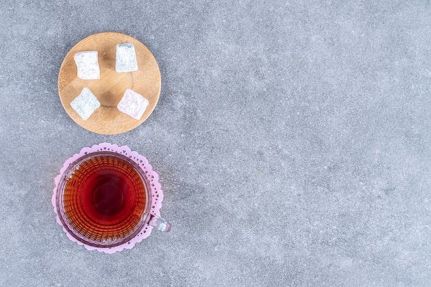 Tasse Tee und süße Bonbons auf Marmoroberfläche