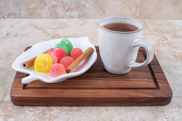 Tasse Tee, Zimt und Marmelade Bonbons auf Holzbrett