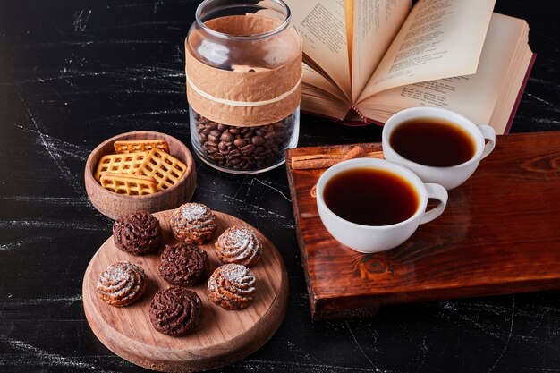 Tassen Kaffee mit Bohnen und Schokoladenpralinen.