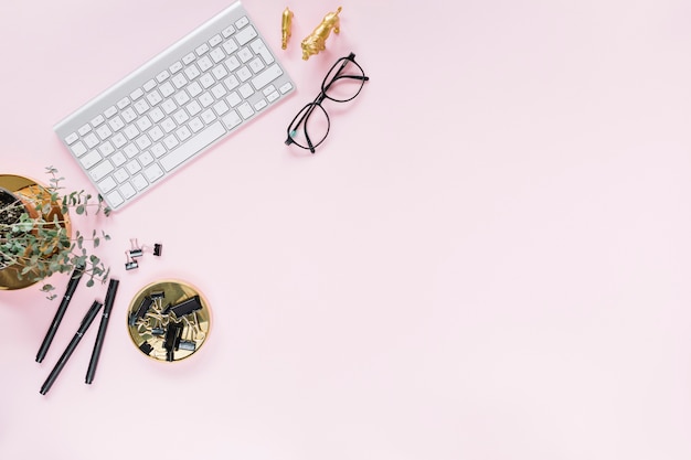 Tastatur; Brille; Filzstifte und Bulldogge Büroklammern auf rosa Hintergrund