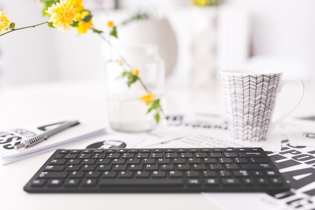 Tastatur mit gelben Blumen und eine Tasse