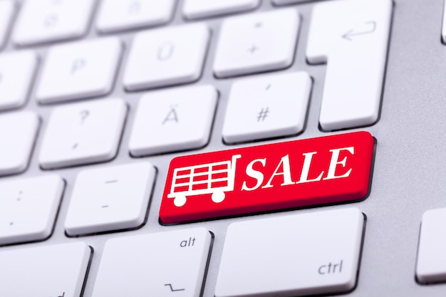 Tastatur mit roter Taste und Wortverkauf darauf mit einem Einkaufswagen daneben