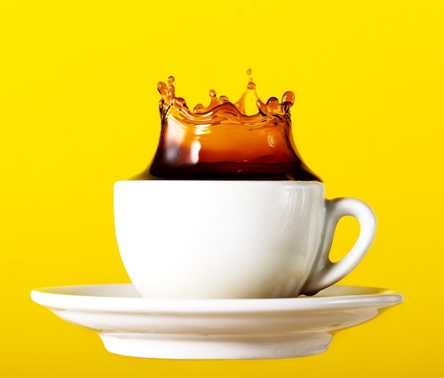 Kostenloses Foto tasty frischen schwarzen kaffee in tasse splash krone auf gelb lebendigen hintergrund. kunstdesign