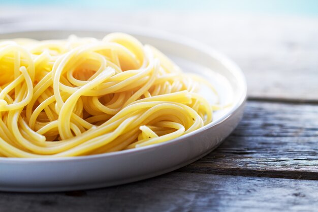 Tasty gekocht bunte Spaghetti Pasta mit frischem Basilikum auf Platte auf Holzuntergrund, closeup.