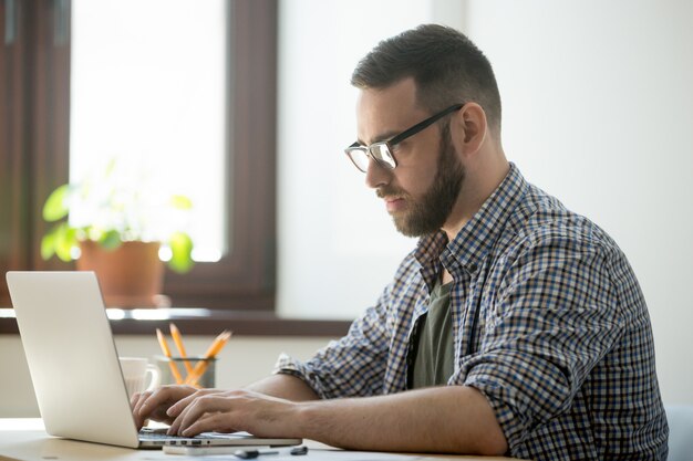 Tausendjähriger Generationsmann, der an Laptop-Computer arbeitet, um Problem zu lösen