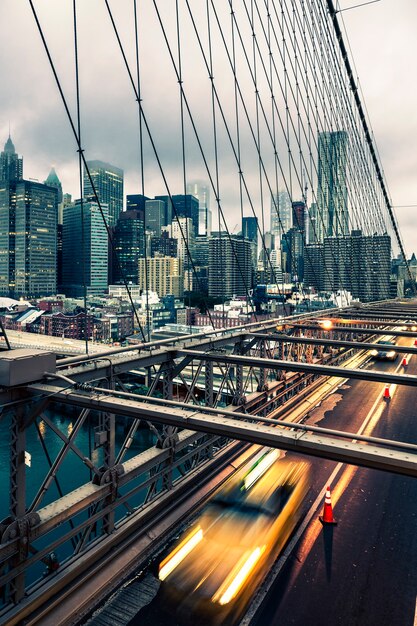 Taxi, das die Brooklyn-Brücke in New York, Manhattan-Skyline im Hintergrund kreuzt