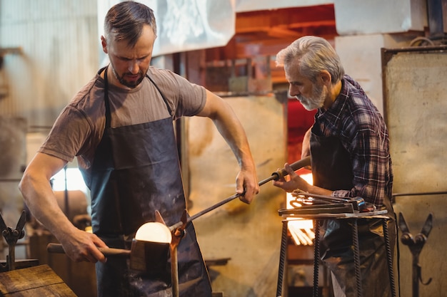 Team von Glasbläsern, die ein geschmolzenes Glas formen und formen