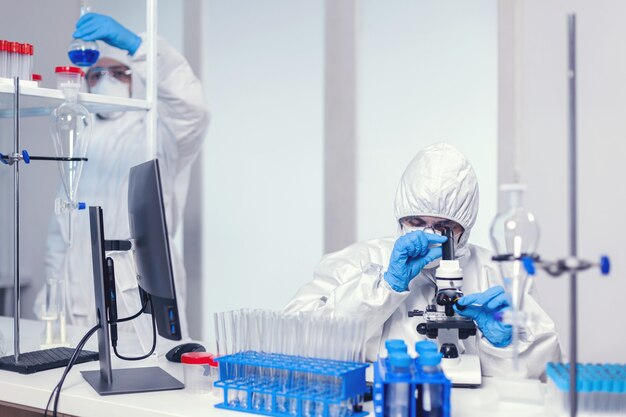 Team von Medizinern in einem modernen Labor, das nach einem Coronavirus-Impfstoff mit PPE sucht. Chemikerforscher während der globalen Pandemie mit Covid-19-Prüfprobe im Biochemielabor