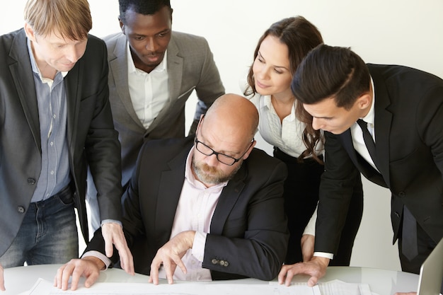 Team von professionellen Ingenieuren, die an Bauprojekten im Sitzungssaal arbeiten, Baupläne analysieren, ernst und konzentriert aussehen.