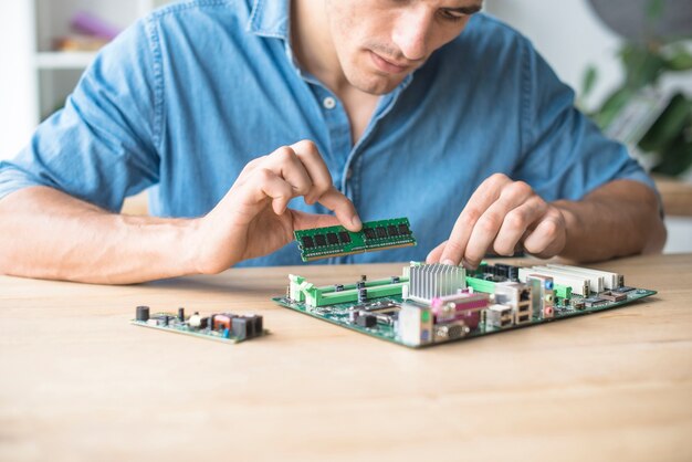 Techniker, der den RAM auf den Sockel des Computermotherboards einfügt