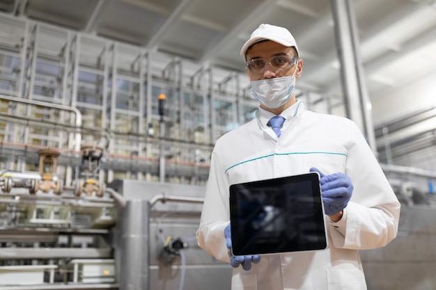 Technologe in einem weißen kittel mit einem tablet in den händen ist im geschäft für die herstellung von butter und käse der produktionsprozess im werk von milchprodukten ein platz für ein etikett