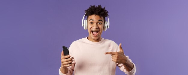 Technologie- und Lifestyle-Konzeptporträt eines glücklichen, fröhlichen jungen Mannes empfehlen einen fantastischen Podcast oder o