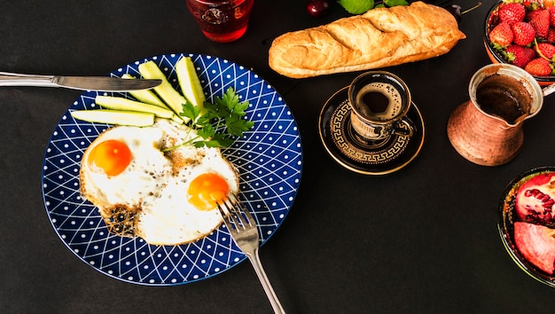 Tee, Brot und gebratenes Omelett mit Scheiben der Gurke auf blauer Platte