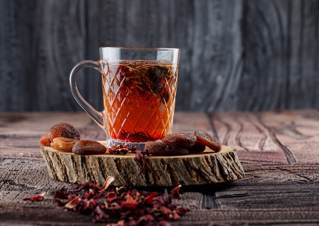 Tee mit getrockneten Früchten und Blumen, Zitrone auf Holz in einer Tasse auf Steinfliesen und Holzoberfläche