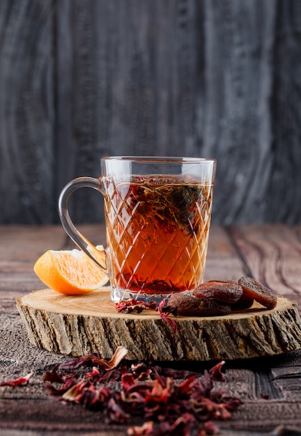 Tee mit getrockneten Früchten und Blumen, Zitrone auf Holz in einer Tasse auf Steinfliesen und Holzoberfläche