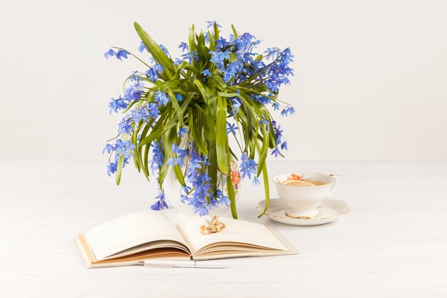 Tee mit Zitrone und Blumenstrauß von blauen Primeln auf dem Tisch