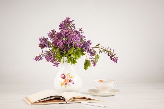 Tee mit Zitrone und Blumenstrauß von lila Primeln auf dem Tisch