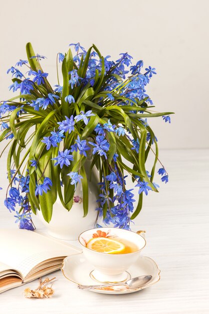 Tee mit Zitrone und Bouquet von blauen Primeln auf dem Tisch