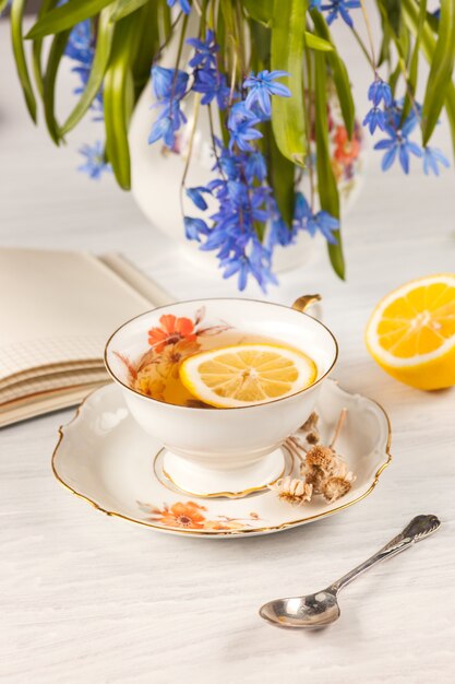 Tee mit Zitrone und Bouquet von blauen Primeln auf dem Tisch