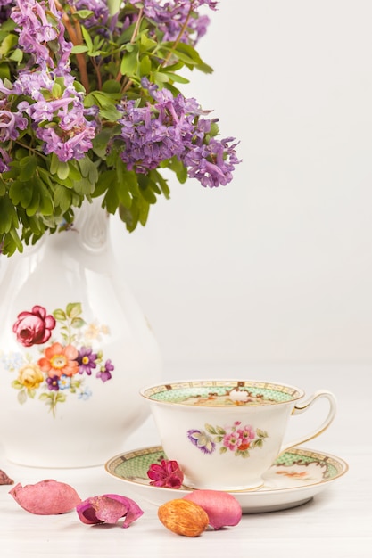 Tee mit Zitrone und Bouquet von lila Primeln auf dem Tisch