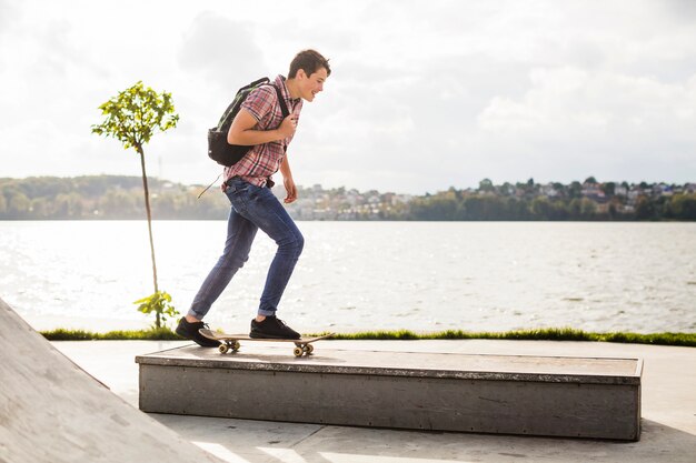 Teeenager, der auf Grenze nahe Wasser Skateboard fährt