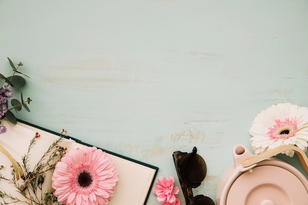 Teekanne in der Nähe von Blumen und Notebook