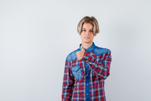 Teen Boy zeigt Daumen im karierten Hemd und sieht zufrieden aus, Vorderansicht.