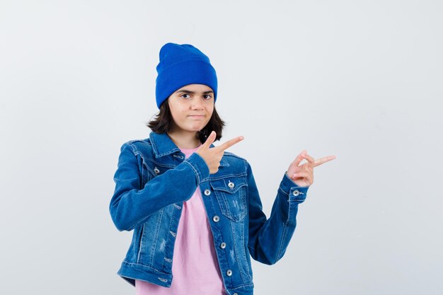 Teen Frau in rosa T-Shirt Jeansjacke Beanie zeigt nach rechts mit Zeigefinger