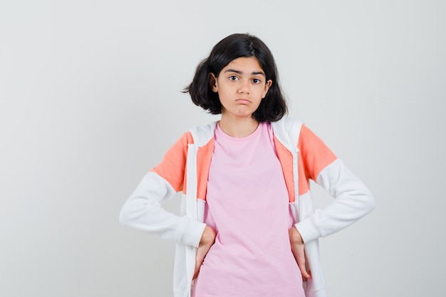 Teen Mädchen in Jacke, rosa Hemd, das Hände auf ihrer Taille hält und müde aussieht