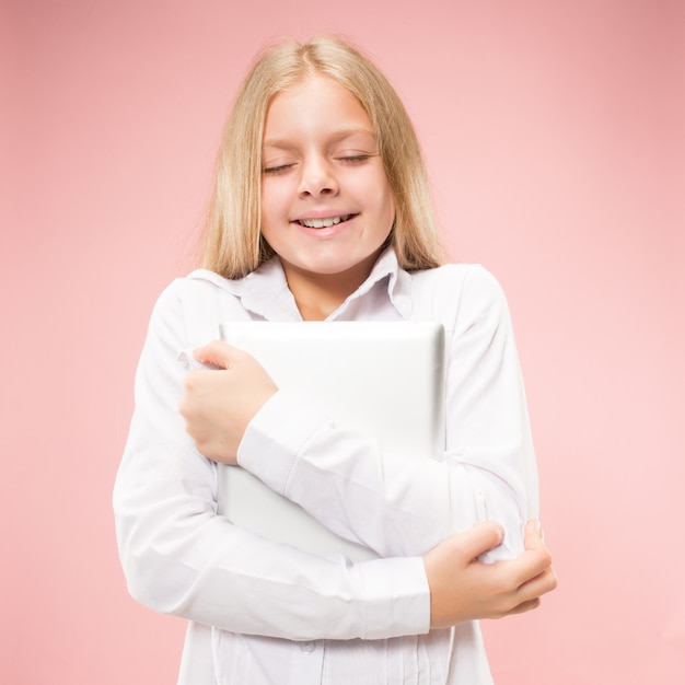 Teen Mädchen mit Laptop. Liebe zum Computerkonzept. Attraktives weibliches Porträt in halber Länge, trendiges rosa Studio-Hintergrundbild.