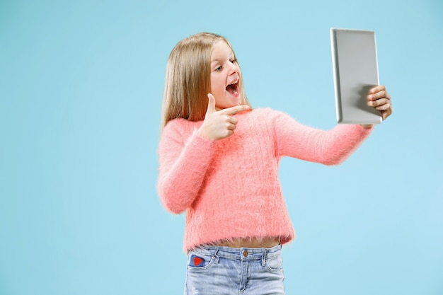 Teen Mädchen mit Laptop. Liebe zum Computerkonzept. Attraktives weibliches Porträt in halber Länge vorne, trendiges blaues Studio-Hintergrundbild. Menschliche Emotionen, Gesichtsausdruckkonzept.