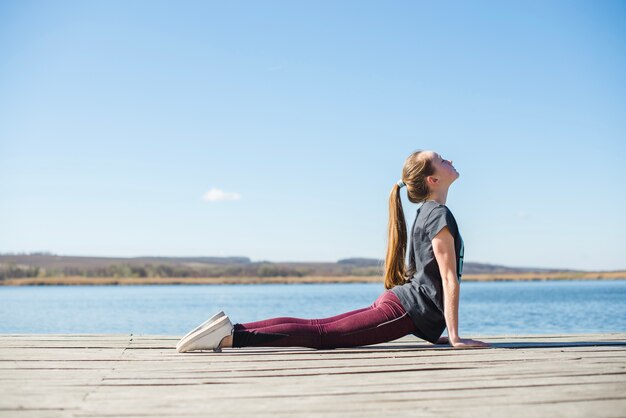 Teenager in nach oben gerichteten Hund Pose am Pier