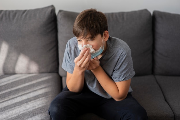 Teenager-Junge, der seine Nase putzt, während er unter Quarantäne gestellt wird