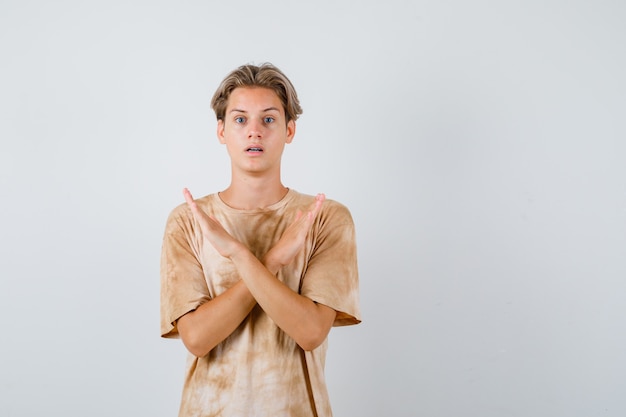 Teenager-Junge im T-Shirt mit Ablehnungsgeste und besorgtem Blick, Vorderansicht.