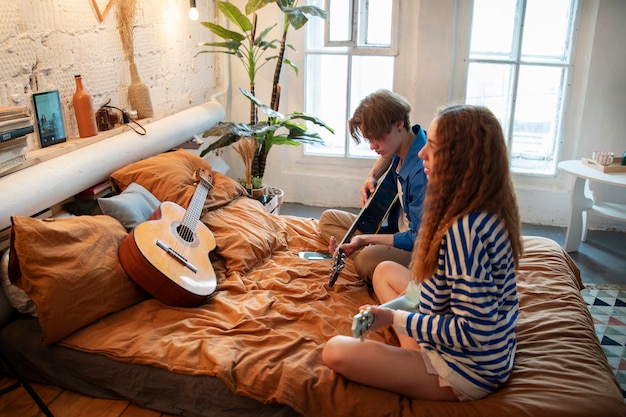 Kostenloses Foto teenager-jungen und -mädchen, die musik in ihrem heimstudio mit gitarre aufnehmen