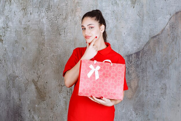 Teenager-Mädchen im roten Hemd mit einer roten Einkaufstasche und sieht verwirrt und nachdenklich aus.