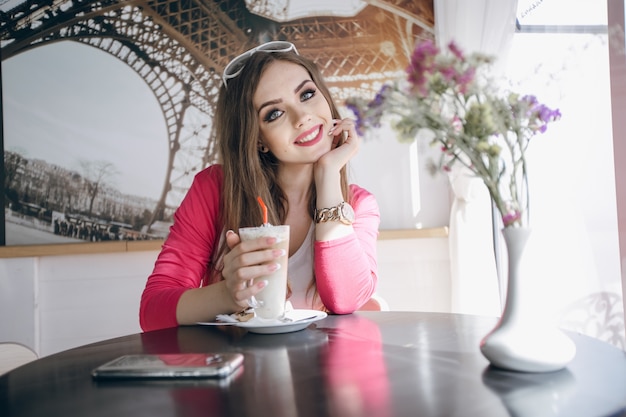 Teenager-Mädchen in einem Glastisch mit einem Schokoladen-Smoothie sitzen