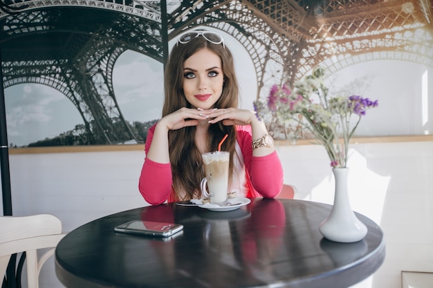 Teenager-Mädchen in einem Glastisch mit einem Schokoladen-Smoothie sitzen