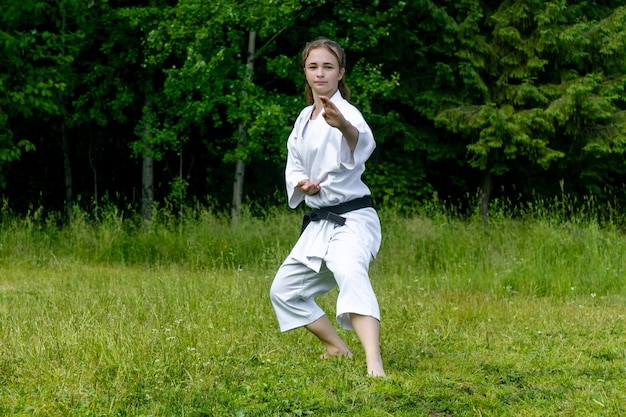 Teenager-mädchen praktiziert karate-kata im freien, führt soto uke oder außerhalb des blocks durch