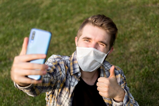 Teenager mit Gesichtsmaske, die ein Selfie nimmt