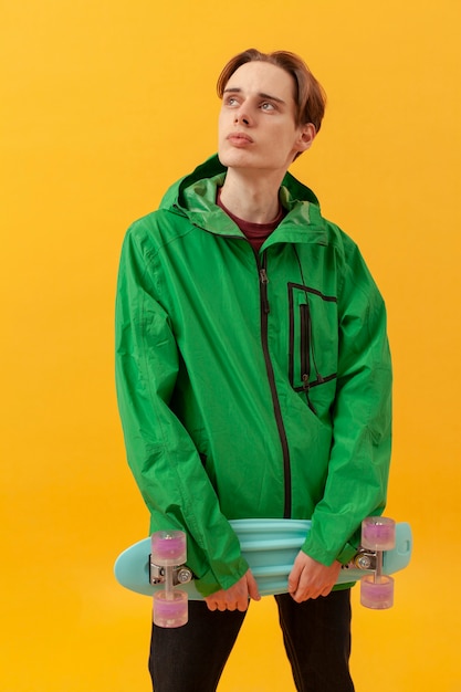 Teenager mit grüner Jacke und Skateboard