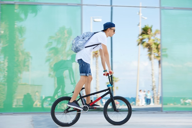 Teenager mit Rucksack und Mütze auf dem Fahrrad