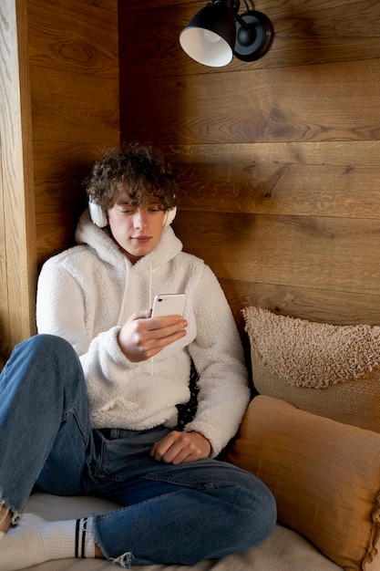 Teenager sitzt in seinem Bett und schaut auf sein Smartphone