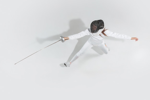Teenie-Mädchen im Fechtkostüm mit Schwert in der Hand lokalisiert auf weißem Hintergrund, Draufsicht
