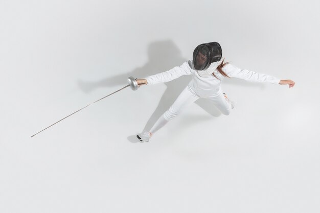 Teenie-Mädchen im Fechtkostüm mit Schwert in der Hand lokalisiert auf weißem Hintergrund, Draufsicht