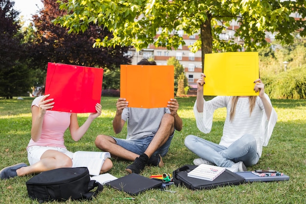 Kostenloses Foto teens, die gesichter mit papieren bedecken