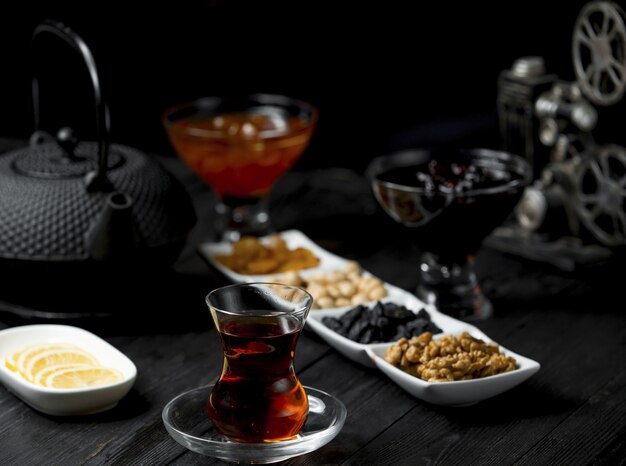 Teepause mit einem Glas Tee und genähten Snacks, Nüssen.