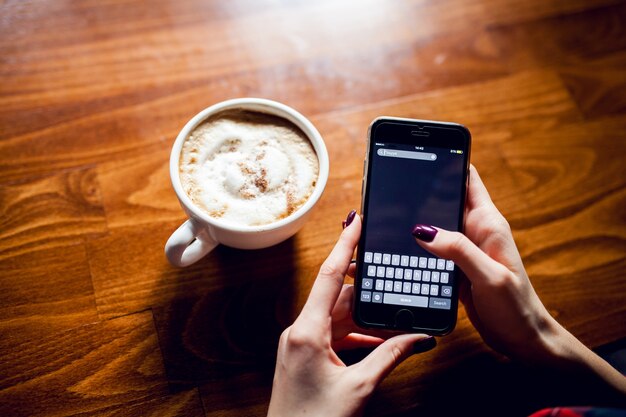 Telefon hölzerner Becher heißer Kaffee